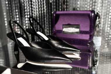 Milan, İtalya - 25 Şubat 2023: Jimmy Choo çantası ve yüksek topuklu ayakkabılar podyum vitrininde, kadın aksesuarlar mağazada sergileniyor
