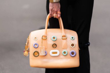 Paris, Fransa - 11 Mart 2025: Kadın şeftali rengi Furla Candy Bag takıyor ve üzerinde pastel yüzük ayrıntıları ve ayı cazibesi var. Sokak tarzı kıyafet ayrıntıları.