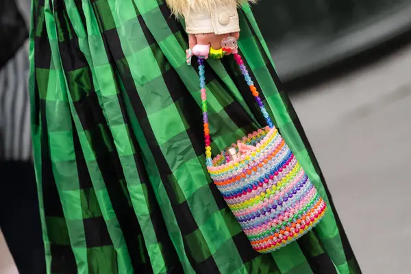 Paris, Fransa - 11 Mart 2025: Oyuncak ve renkli yüzüklerle dolu gökkuşağı boncuklu kova çanta, yeşil pileli midi etekli. Sokak tarzı kıyafet ayrıntıları.