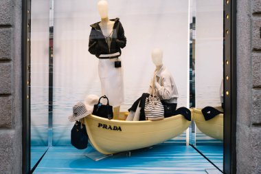 Milan, İtalya - Nisan 08, 2025: Milano 'daki Prada mağaza vitrininde yaz modasına sahip mavi bir teknede mankenler sergilenmektedir. Üst düzey tasarımcı perakende satış sahnesi.