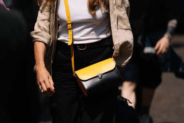 Milan, İtalya - 16 Haziran 2023: kadın sarı el çantası takıyor. Moda kıyafetleri, sokak tarzı.