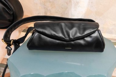 Milan, İtalya - Nisan 08, 2025: Jil Sander yumuşak katlanmış ve geniş kayışlı siyah deri omuz çantası. Milan moda butik iç mekanında gösterildi.