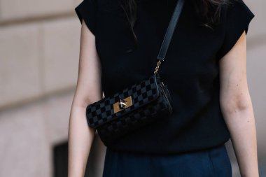 Milan, İtalya - 19 Haziran 2023: Kadın Giorgio Armani kareli siyah çanta takıyor. Moda kıyafetleri, sokak tarzı.
