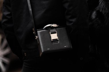 Milan, İtalya - 25 Mart 2024: Kadın siyah deri Heliot Emil Kutu çanta giyiyor. Moda kıyafetleri, sokak tarzı.