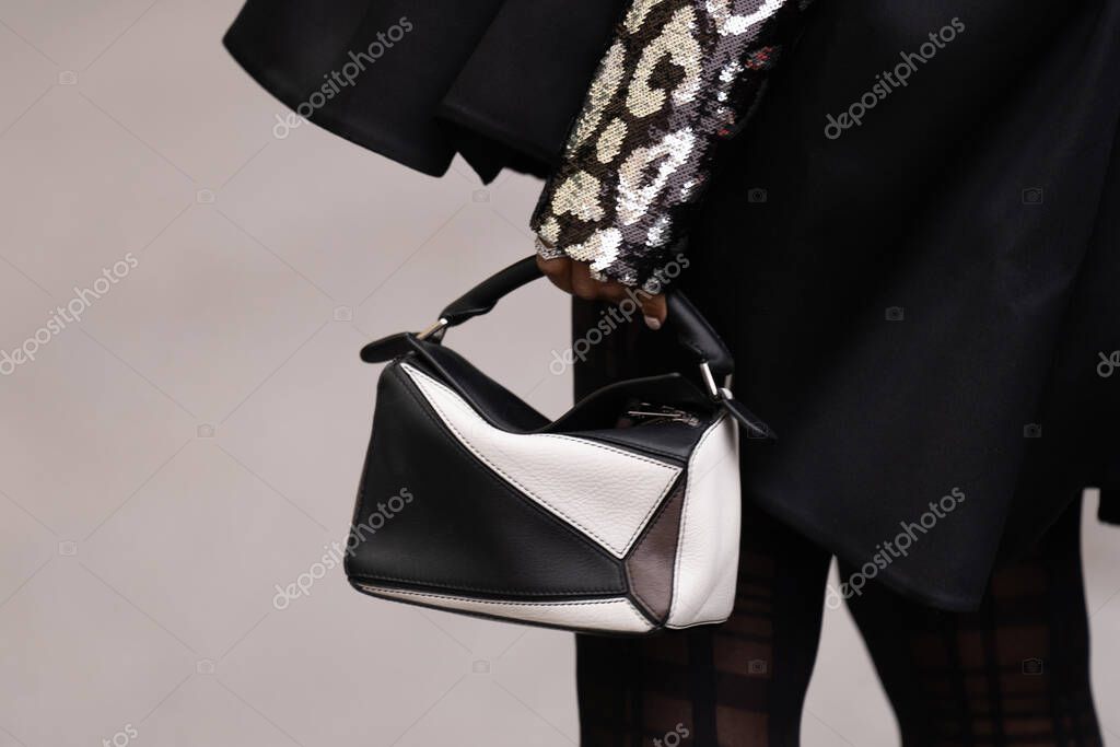 Milan, Italy - February, 26, 2023: Woman wears Loewe small puzzle black leather handbag. Fashion outfit detail, street style