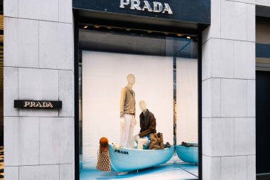 Milan, İtalya - Nisan 08, 2025: Milano 'daki Prada mağaza vitrininde yaz modasına sahip mavi bir teknede mankenler sergilenmektedir. Üst düzey tasarımcı perakende satış sahnesi.
