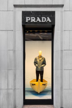 Milan, İtalya - 08 Nisan 2025: Milano 'da Prada vitrinleri. Kot ceketli erkek manken sarı botun içinde duruyor. Moda mağazası konsepti.