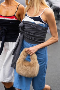 Paris, Fransa - 11 Mart 2025: Kadınlar bronz, sahte kürk Miu Miu çanta ve katmanlı Miu Miu kıyafeti giyerler. Sokak tarzı kıyafet ayrıntıları.