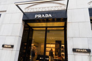 Milan, İtalya - Nisan 08, 2025: Milano 'daki Prada butiğinin dışı cam kapılar ve lüks iç mekanı görünür. Zarif tasarımcı moda mağazası önü.