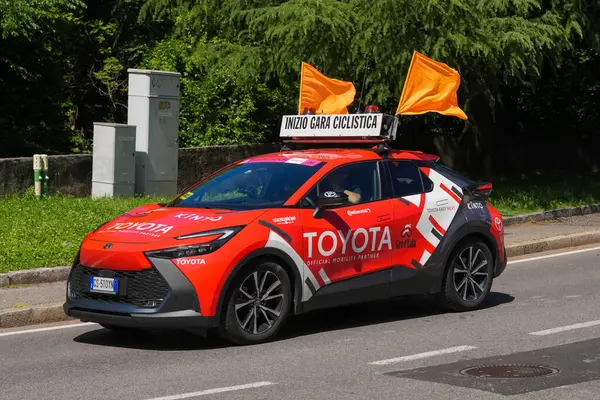 Lecco, İtalya - 29.05.2025: Giro dItalia yarış arabası Toyota, turuncu bayraklı ve açık havada bisiklet yarışması sırasında tabelalı. Giro dItalia, her yıl düzenlenen çok aşamalı bisiklet yarışı.