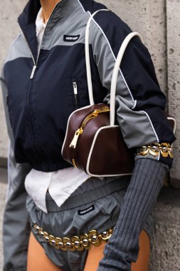 Paris, Fransa - 11 Mart 2025: Kahverengi Miu Miu çanta beyaz boru ve altın fermuarlı spor ceket ve zincir detay ile eşleştirildi. Sokak tarzı.