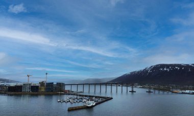 Tromso köprüsü deniz, gökyüzü ve mimariyle çevrili sakin sulara yansıyor..