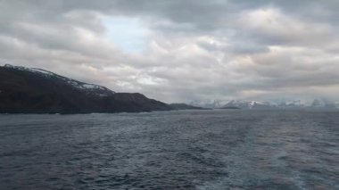 Sakin sahne: Honningsvg, Norveç. Görkemli dağlar, dingin göl, doğanın güzelliğini yansıtan karla kaplı dağlar. 