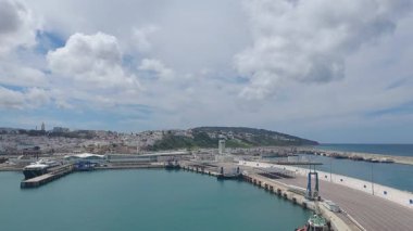 Fas tangier Nisan 26 2024 Canlı şehir manzarası ve dramatik bulutlu gökyüzü altında geniş okyanus ile Tangier 'in hareketli limanının panoramik bir görüntüsü, canlı deniz endüstrisini ve doğal kıyı güzelliğini vurguluyor..