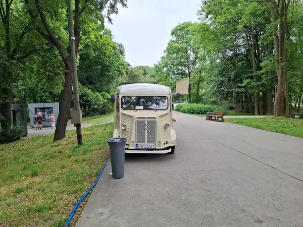 Poland gdansk 7 Haziran 2024. Yeşillik ve ağaçlarla çevrili sakin bir yolda park etmiş klasik bir yemek kamyonu berrak bir gökyüzü altında sakin ve misafirperver bir atmosfer yaratıyor. Açık hava perakende ve yaşam tarzı kavramları için ideal.