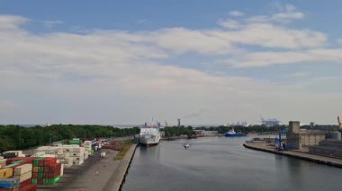 30 Mayıs 2024 Polonyalı gdansk. Parlak mavi gökyüzünün altında, nakliye konteynırları ve kenetlenmiş bir gemiyle hareketli bir sanayi limanı..