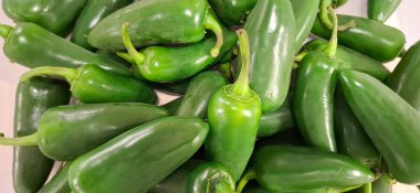 Canlı yeşil jalapeo biber koleksiyonu. Mutfak kullanımı ve fotoğrafçılık için ideal. Bu biberler tazeliği ve parlak dokularını tasvir ediyor. 