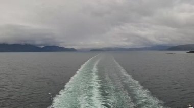 Serene Waterscape with Boat Wake and Bulcast Sky in a Scenic Fjord