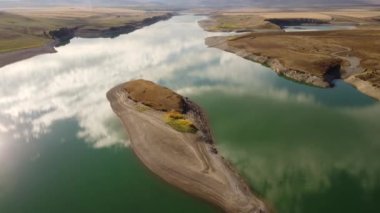 Gökyüzü yansıması, arka planda Kanadalı Rocky 'lerin olduğu puslu bir günde Old Man Baraj Alberta Kanada' da bir gölün üzerinde çekim olduğunu gösteriyor.