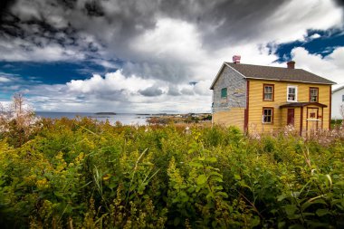 Sonbahar renklerinde Atlantik Okyanusu 'na bakan terk edilmiş ev Elliston Newfoundland Kanada yakınlarında derin mavi dramatik bir gökyüzü altında.