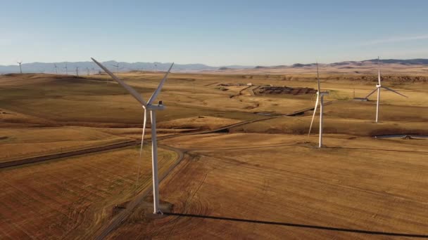 遠くカナダのロッキー山脈と丘陵地帯の上の風力発電所の高い空中風車の閉鎖 — ストック動画