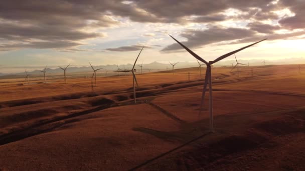 Aerial Windmills Spinning Cinematic Shot Sunset Rolling Hills Distant Mountains — Video Stock