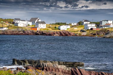 Maritime homes built on rocky cliffs in a small fishing community overlooking the Atlantic Ocean in Keels Newfoundland Canada.