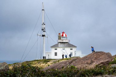Cape Spear Newfoundland Canada, September 21 2022: People outdoors walking alongside a historic lighthouse at a popular tourist attraction on the East Coast of Canada. clipart