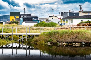 Old Bay Pond 'daki tahta köprünün su yansıması. Renkli Newfoundland evleri ve Bonavista Kanada' daki elektrik direklerine bakıyor..