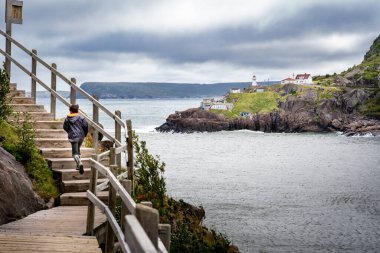 St. John 's Newfoundland Kanada, 21 Eylül 2022: Genç bir çocuk Fort Amherst Deniz fenerine bakan Battery Road yürüyüş yolu boyunca bir dizi ahşap basamak koşar.