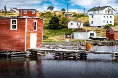 Doğu kıyısındaki evler ve balıkçılık malzemeleri Kanada 'nın Newfoundland Limanı yakınlarındaki Trinity Körfezi' ne bakan eski ahşap rıhtımlarda..