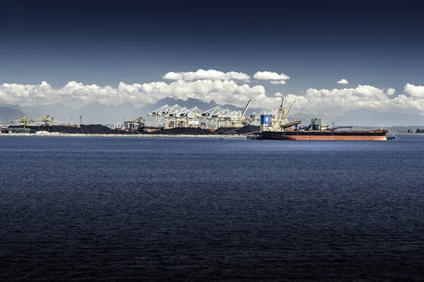 stock image Delta British Columbia Canada, July 23 2022: A freighter is loaded with coal by conveyer belts mined from Canadian natural resources overlooking distant mountains.