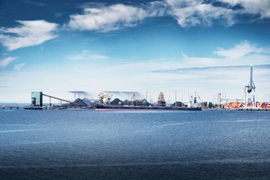 Tsawwassen British Columbia Canada, July 11 2023: A freighter is loaded with coal mined from Western Canada at the Robert Bank Coal Terminal with conveyer belts and dust control spray. clipart