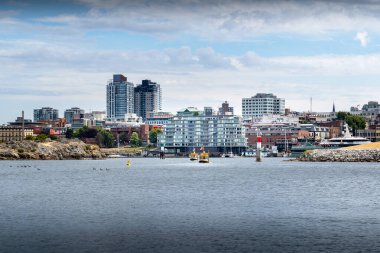 Victoria British Columbia Canada, 12 Temmuz 2023: Bir çift su taksi botu şehir merkezindeki apartman ve şehir merkezinden geçiyor. .