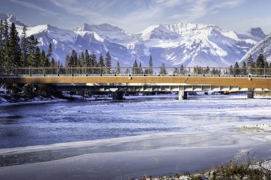 Banff Alberta Kanada 'daki Kanada Rocky Dağları' na bakan yaya köprüsü Bow Nehri 'ni geçer..