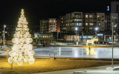 Calgary Alberta Canada, 30 Kasım 2023: Geceleri açık havada kayak pisti ve noel ışıkları Üniversite Bölgesi 'ne tepeden bakan apartman binaları ve buz patencileri.