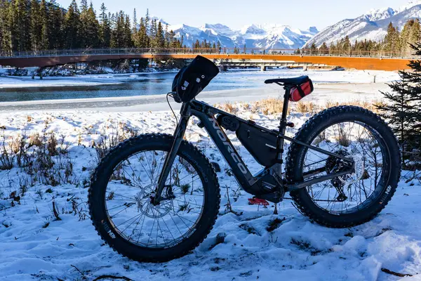 Banff Alberta Canada, Aralık 01 2023: Kar altında, yaya köprüsüne ve Kanada Rocky Dağları 'na bakan şişman bir bisiklet..