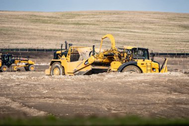 Airdrie Alberta Canada, 21 Mayıs 2024: Gelecekteki konut alanları için arazi geliştiren bir inşaat alanında tekerlek traktör kazıyıcısı.