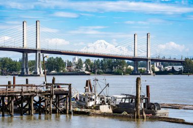 Coquitlam Limanı İngiliz Kolombiya Kanada, Haziran 09 2024: Arka plan 'da Baker Dağı ile bir kablo asma köprüsüne bakan balıkçı teknesi.