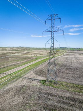 Isolated electrical pylon standing tall on agriculture fields with country road at background. clipart