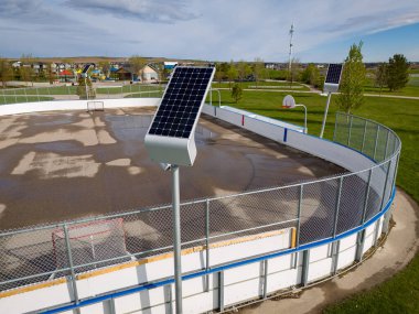 Airdrie Alberta Canada, May 05 2024: Solar panels charging outdoor lights aerial shot overlooking outdoor rink and basketball court at a community park. clipart