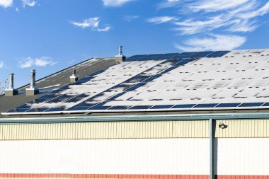 Snow melting off solar panels outfitted with snow guards at a local community centre and hockey rink in Calgary Alberta Canad clipart