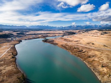 Morley Alberta 'nın uzak bir kasabasına bakan su yolu manzaralı ve arka planda 1A karayolu ve Kanada kayalıkları var..