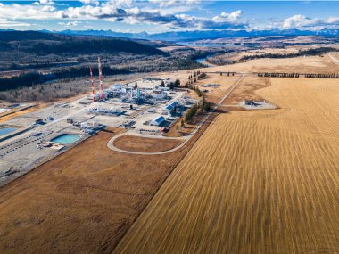 Cochrane Alberta Canada, 30 Ekim 2024: Çayırlara tepeden bakan Doğal Gaz Fabrikası manzarası ve arka planda Kanada Kayalıkları olan yuvarlanan tepeler.