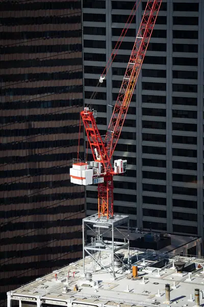 Calgary Alberta Canada, Ekim 09 2024: İnşaat vinci inşaat malzemelerini kaldıran bir vinç ile şehir merkezinin tepesinde.