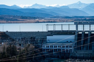 Cochrane Alberta Kanada yakınlarındaki Kanada Rocky Dağları ile göle bakan elektrik hatlarıyla elektrik üreten hidrobaraj..