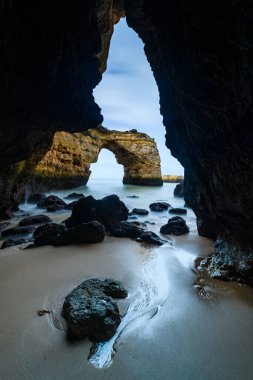 Sahilde, Algarve 'deki mağarada kayalar uzanıyor.