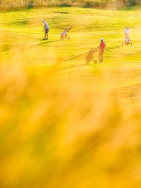 Golf sahasındaki insanların önünde çimenler.