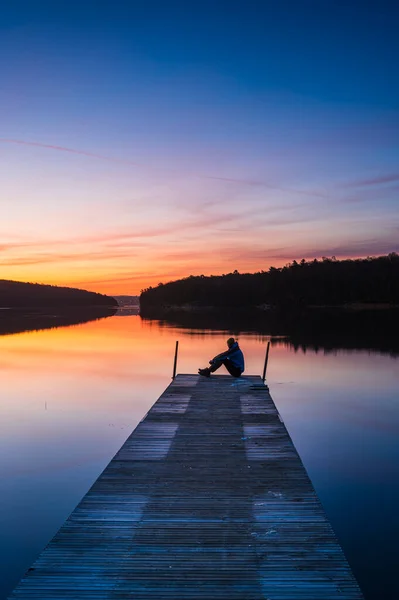 stock image Man sitting on jetty at sunrise