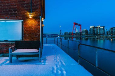İsveç, Göteborg 'da soğuk bir kış sabahı, bir yerleşim bölgesinin nehir rıhtımı boyunca uzanan aydınlık mavi bir binayı gözler önüne serdi..